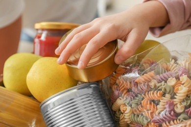 Photo of Girl taking food out of donation box, closeup