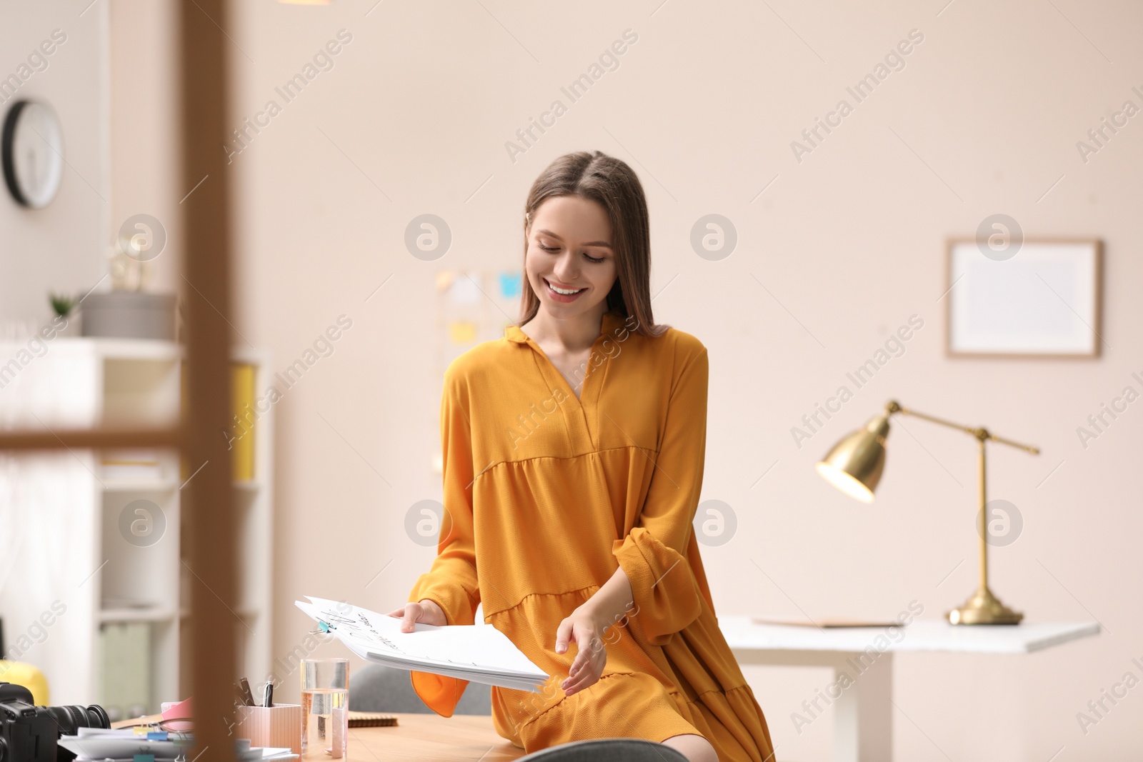 Photo of Young journalist with papers at workplace in office