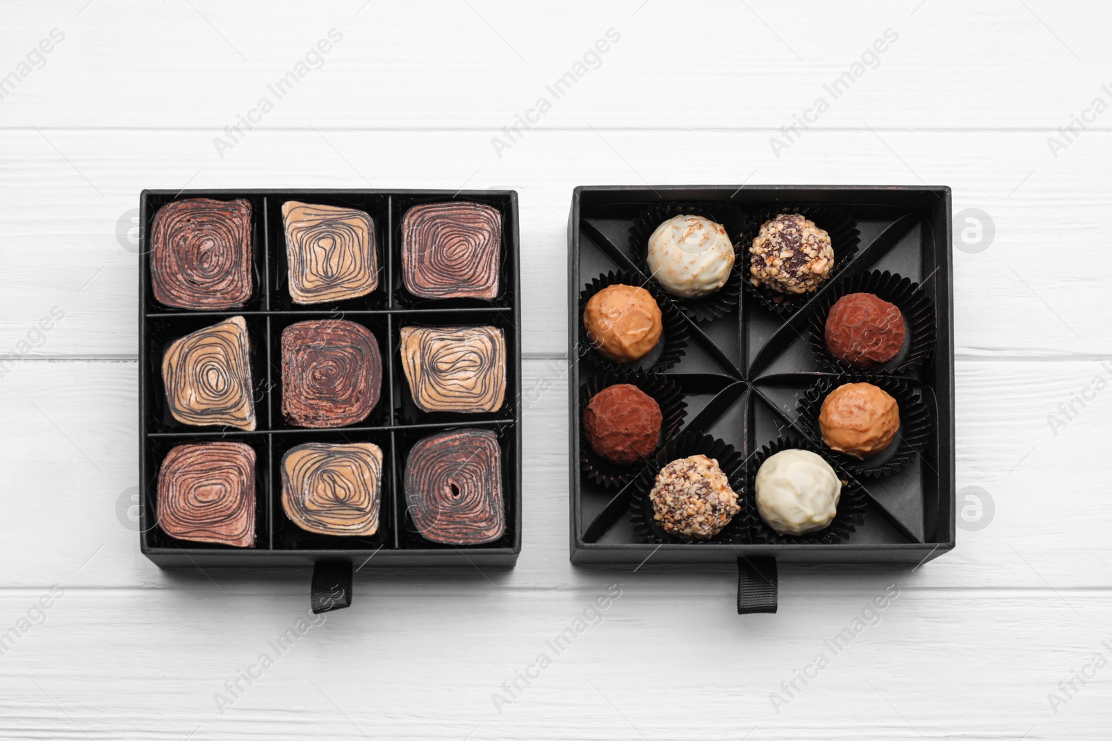 Photo of Boxes of tasty chocolate candies on white wooden table, flat lay