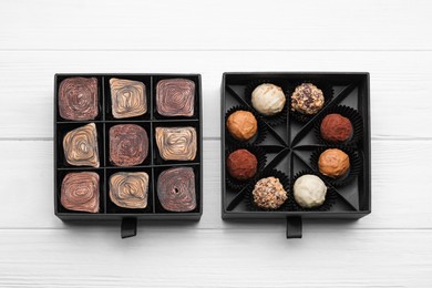 Boxes of tasty chocolate candies on white wooden table, flat lay