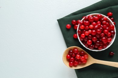 Photo of Cranberries in bowl and spoon on white table, top view. Space for text