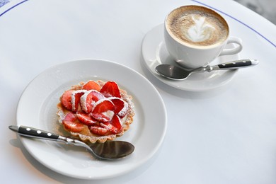 Photo of Plate with tasty dessert and cup of fresh coffee on round table in morning