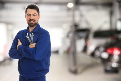 Image of Professional mechanic with wrenches at tire shop. Space for text
