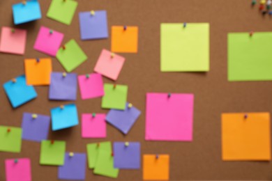 Photo of Blurred view of corkboard filled with colorful notes and pins