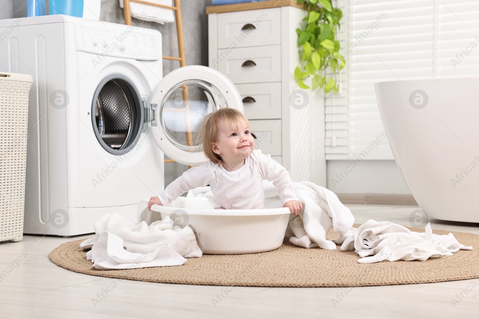 Photo of Little girl among baby clothes in bathroom