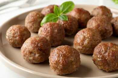 Photo of Tasty cooked meatballs with basil on plate, closeup