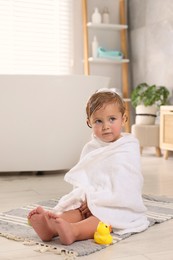 Cute little girl wrapped with towel after bath at home
