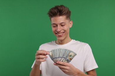 Happy man with dollar banknotes on green background