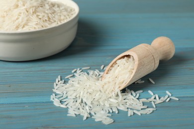 Photo of Raw basmati rice in scoop on light blue wooden table, closeup