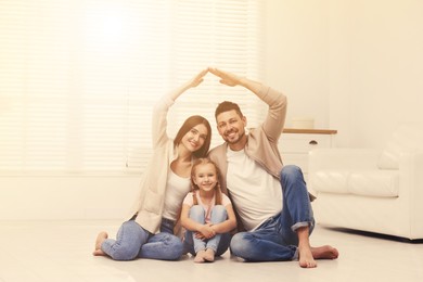 Happy family forming house roof with their hands at home. Insurance concept