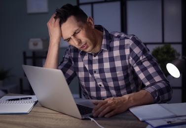 Photo of Overworked man with headache in office