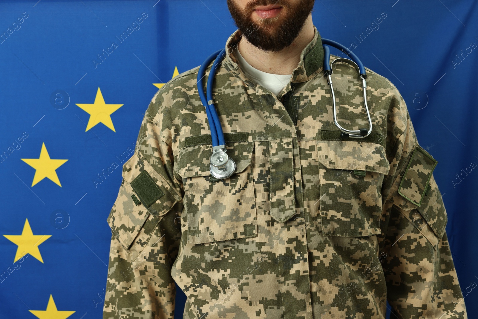 Photo of Man in military uniform with stethoscope against flag of European Union, closeup. Health care concept