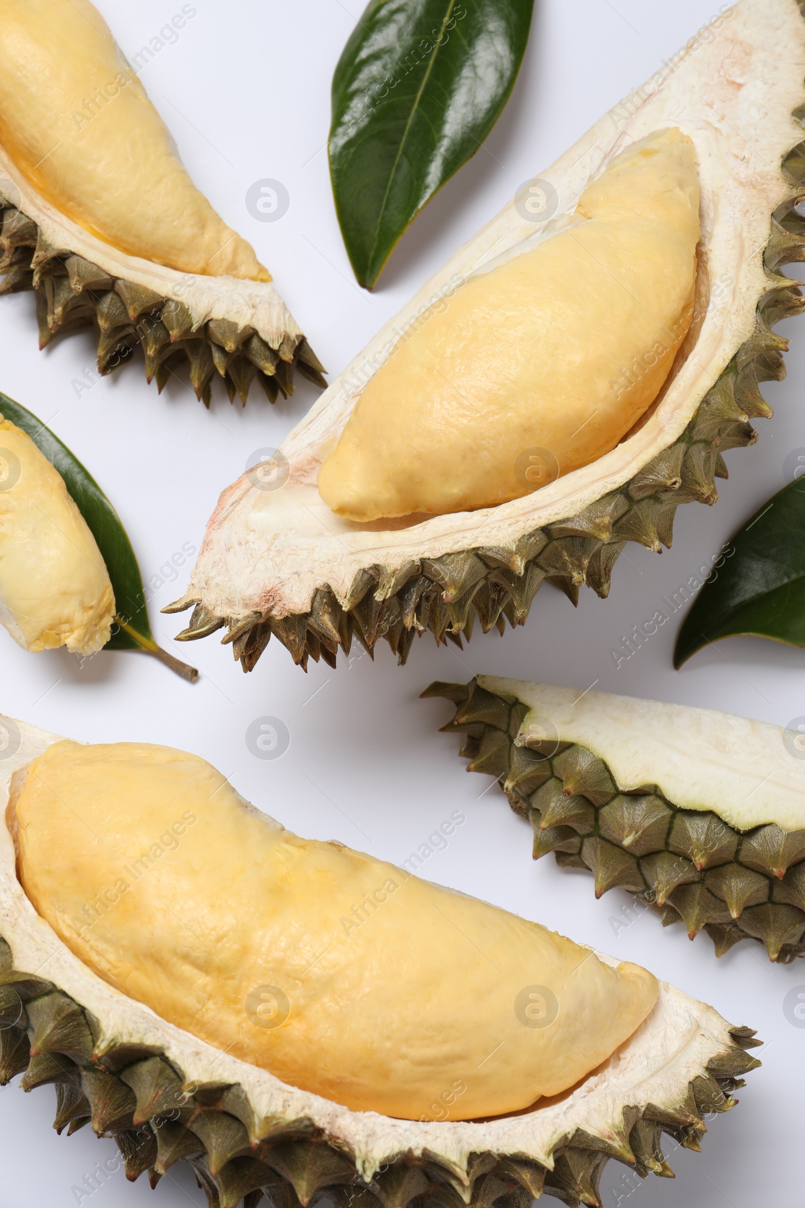 Photo of Pieces of fresh ripe durian and leaves on white background, flat lay