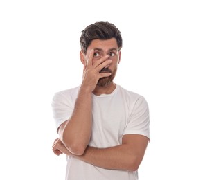 Embarrassed man covering face with hand on white background