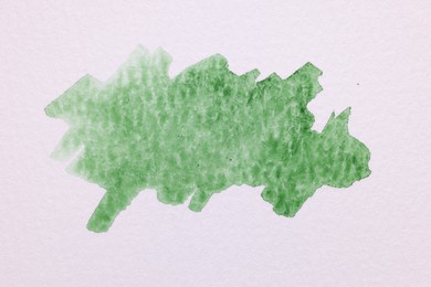 Blot of green watercolor paint on white paper, top view