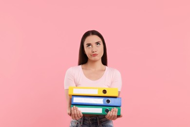 Disappointed woman with folders on pink background