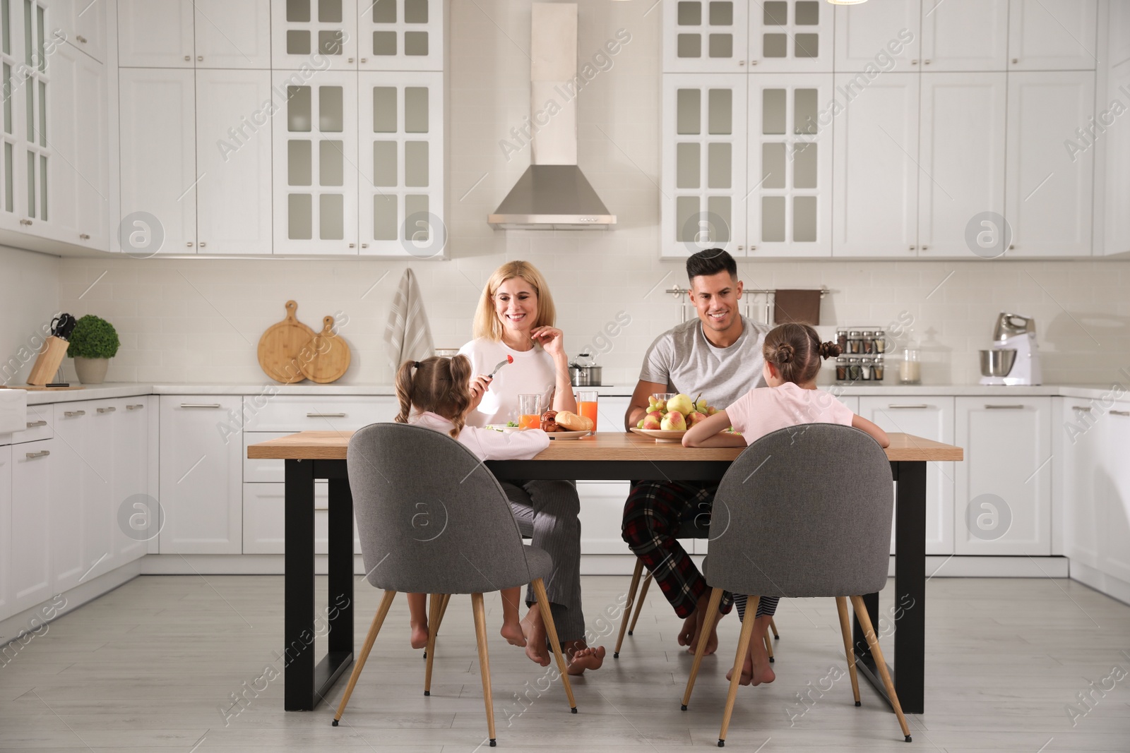 Photo of Happy family having breakfast together at table in modern kitchen