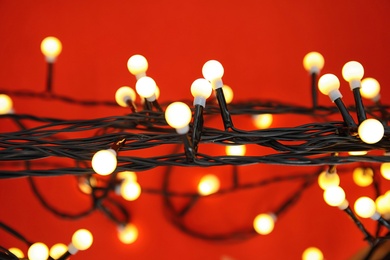 Glowing Christmas lights on color background, closeup