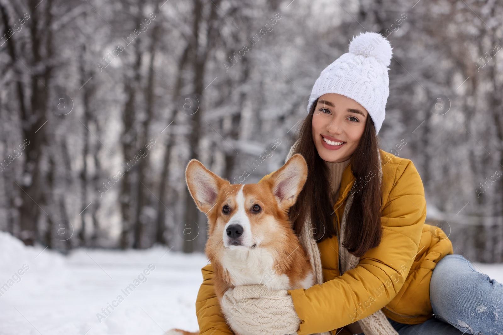 Photo of Woman with adorable Pembroke Welsh Corgi dog in snowy park, space for text