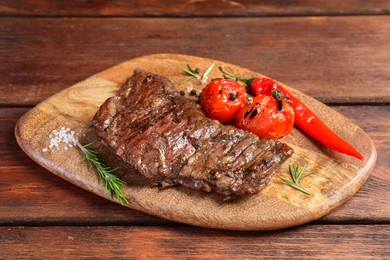 Photo of Delicious roasted beef meat, vegetables and spices on wooden table