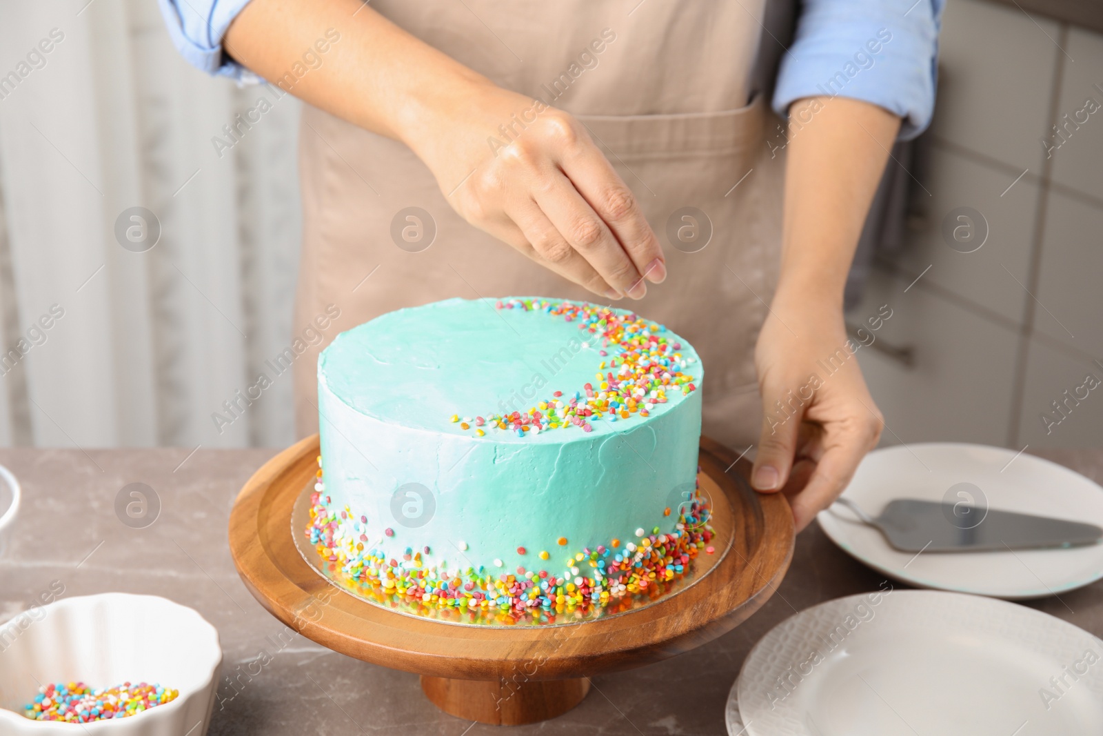 Photo of Woman decorating fresh delicious birthday cake in kitchen, closeup