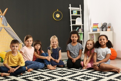 Photo of Cute little children sitting on floor indoor in kindergarten. Indoor activity