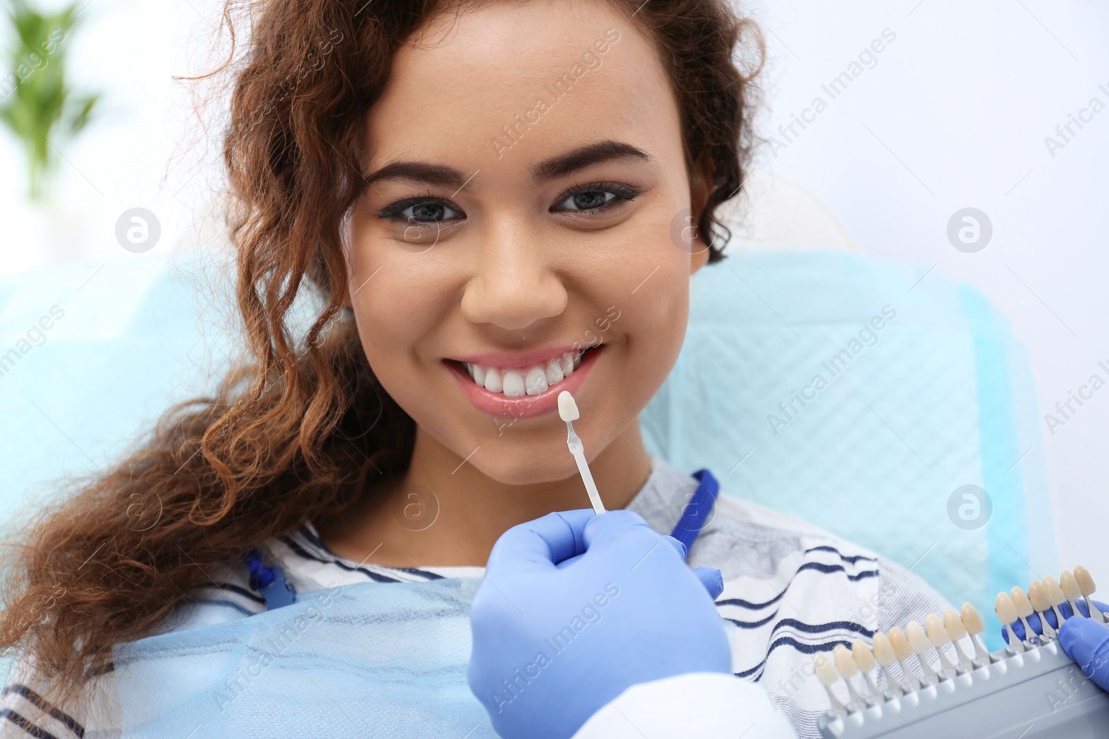 Photo of Dentist matching patient's teeth color with palette in office