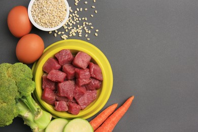 Photo of Raw meat in bowl and healthy products for pet on black background, flat lay. Space for text