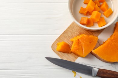Pieces of boiled pumpkin and knife on white wooden table, flat lay with space for text. Child's food