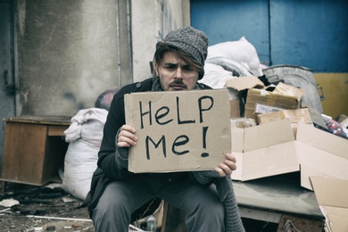 Photo of Poor young man with HELP ME sign at dump