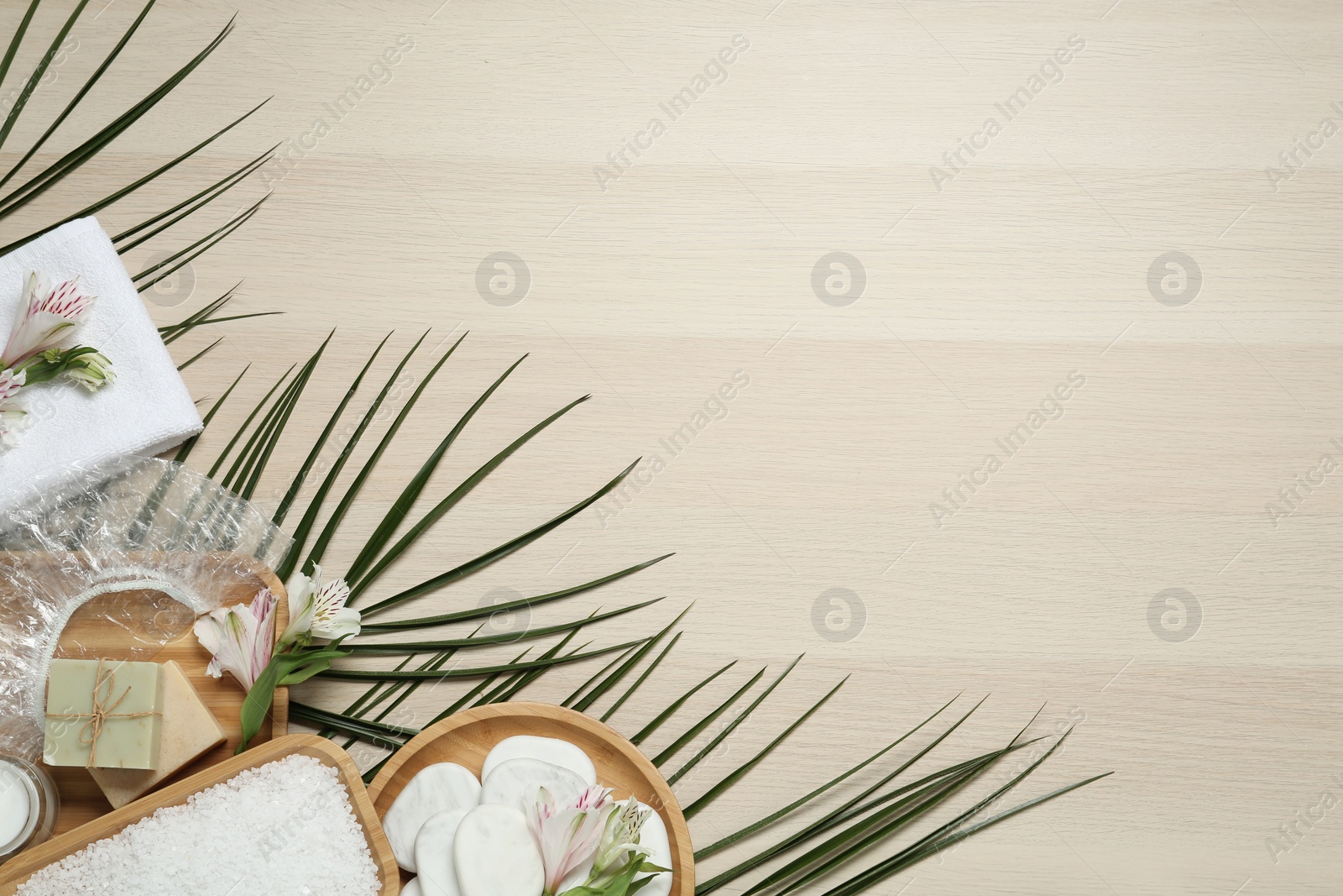 Photo of Flat lay composition with shower cap and spa stones on wooden background. Space for text