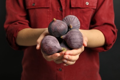 Woman holding tasty raw figs on black background, closeup