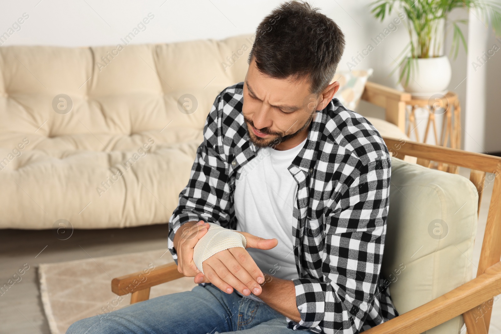 Photo of Man with hand wrapped in medical bandage at home