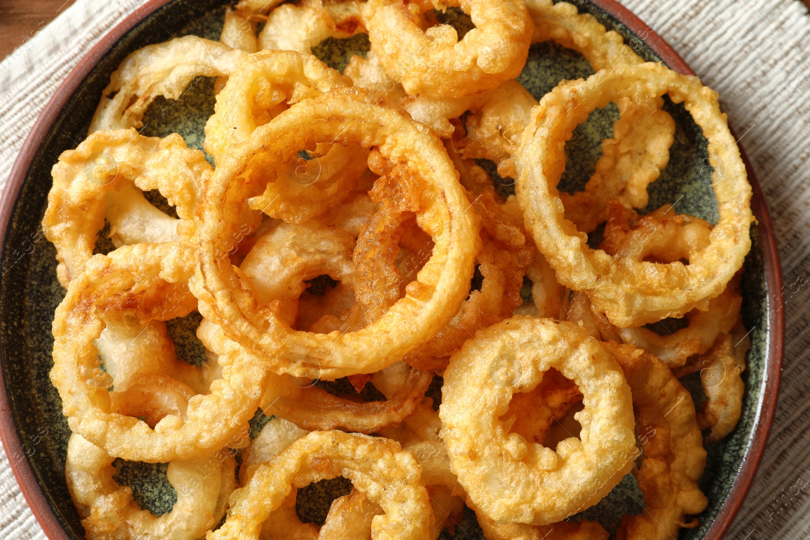 Photo of Homemade crunchy fried onion rings on plate, top view
