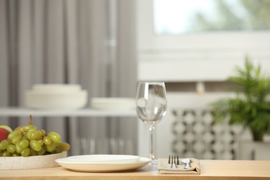 White plates and wineglass served for dinner on wooden table