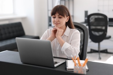 Photo of Woman watching webinar at table in office