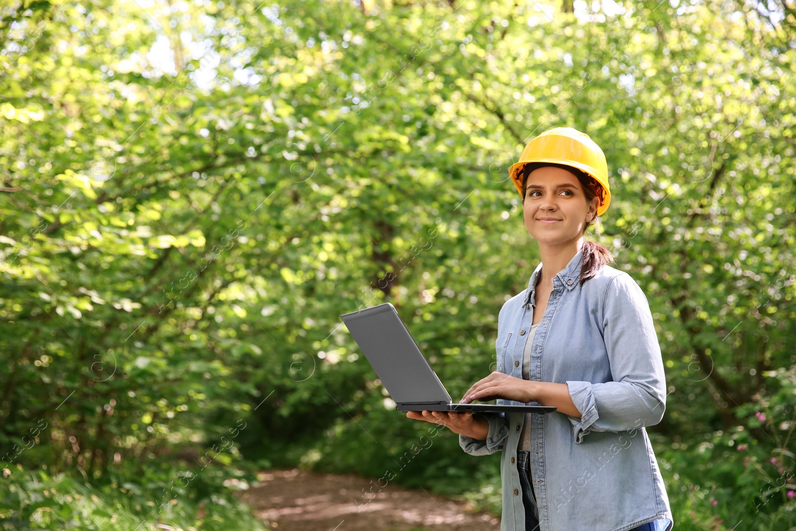 Photo of Forester with laptop examining plants in forest, space for text