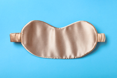 Photo of Beige sleeping mask on light blue background, top view. Bedtime accessory