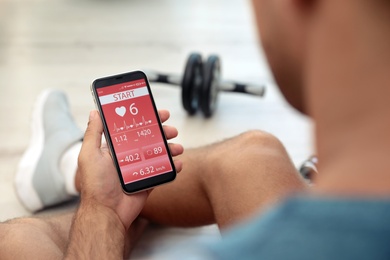 Man using fitness app on smartphone indoors, closeup