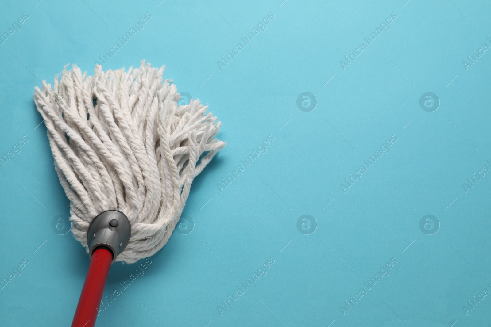 Photo of Mop with plastic handle on light blue background, top view. Space for text