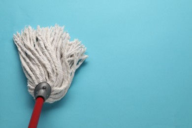 Photo of Mop with plastic handle on light blue background, top view. Space for text