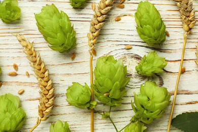 Flat lay composition with fresh green hops and wheat ears on white wooden table