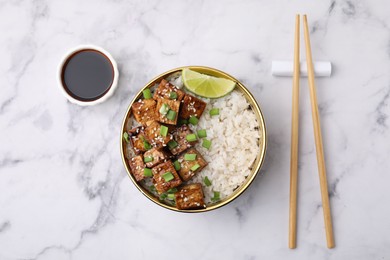 Delicious rice with fried tofu and green onions served on white marble table, flat lay