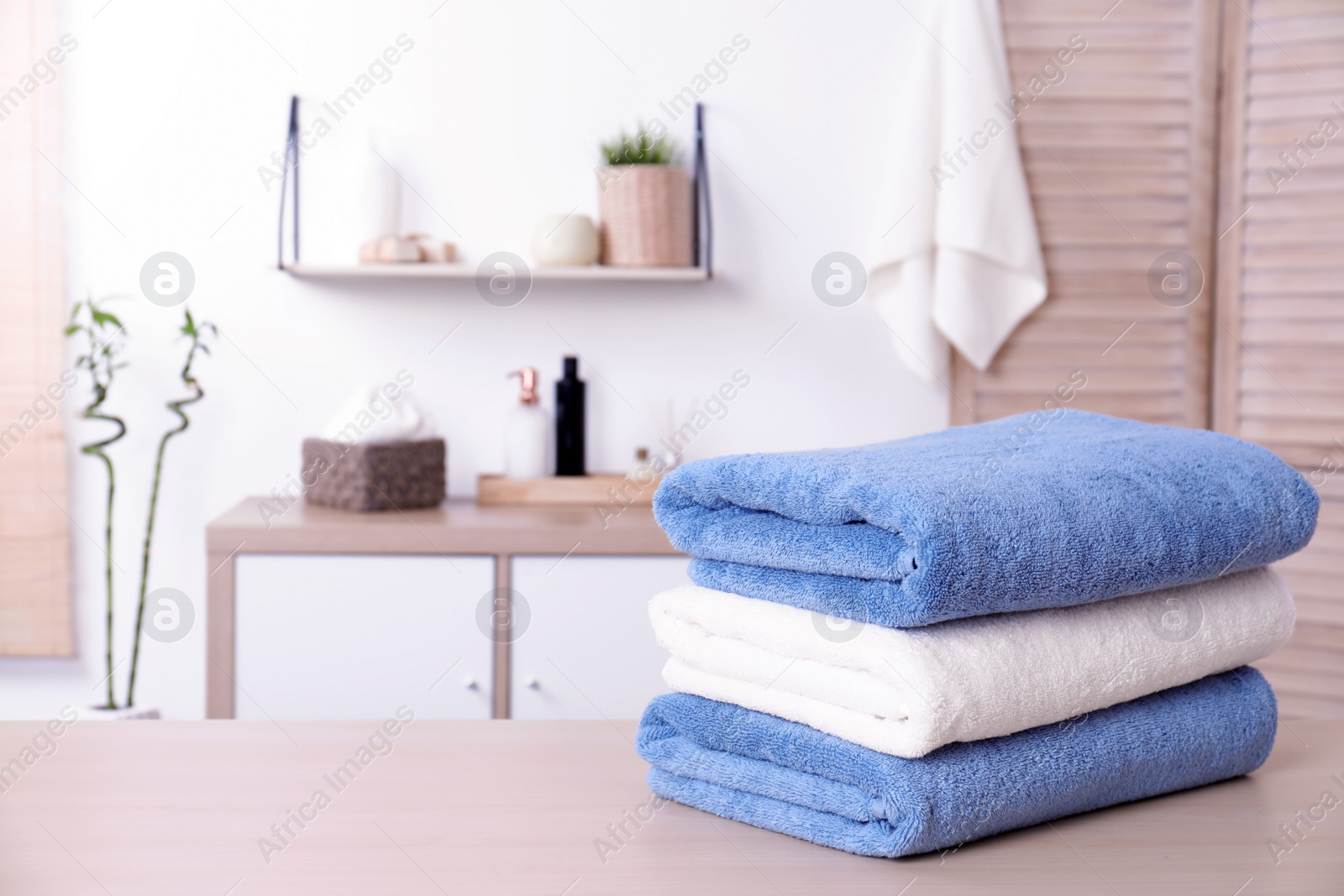 Photo of Stack of fresh towels on table in bathroom. Space for text