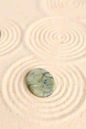 Photo of Zen garden stone on beige sand with pattern