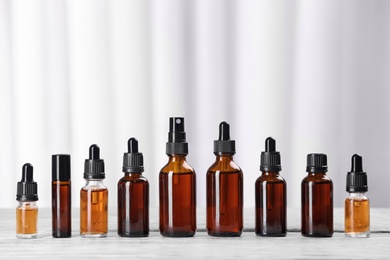 Photo of Bottles of essential oils on table against light background. Cosmetic products