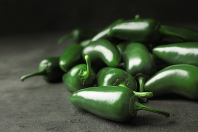 Photo of Pile of green hot chili peppers on grey table, closeup. Space for text