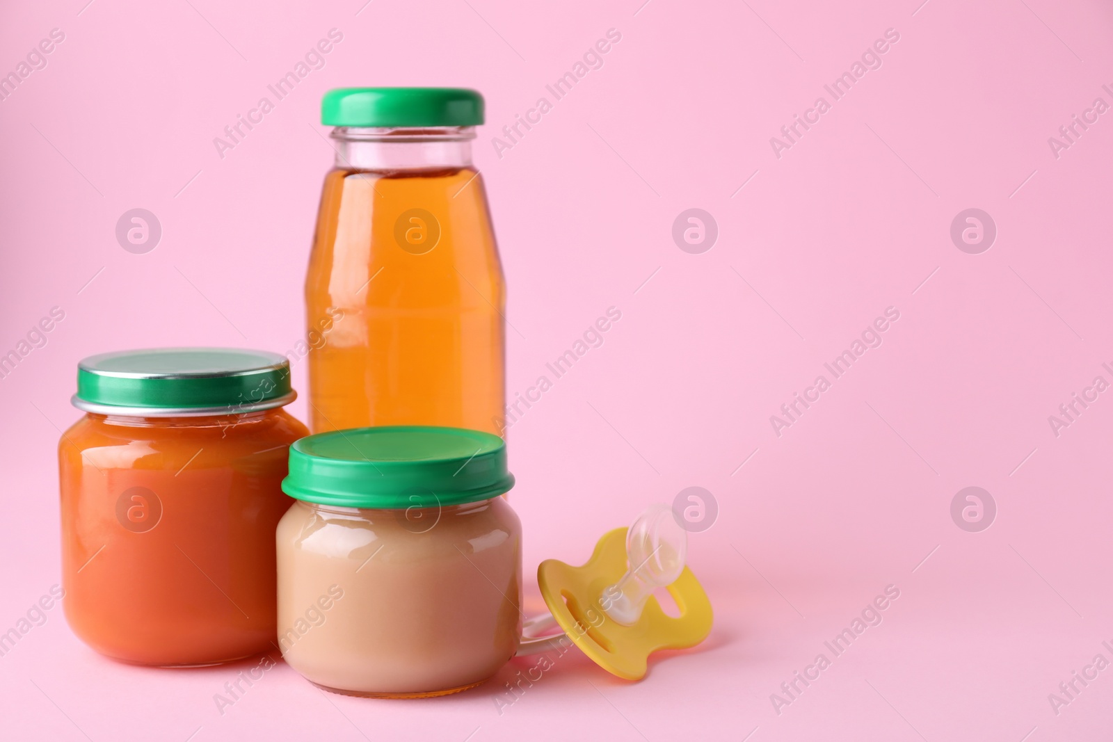 Photo of Healthy baby food, juice and pacifier on pink background, space for text