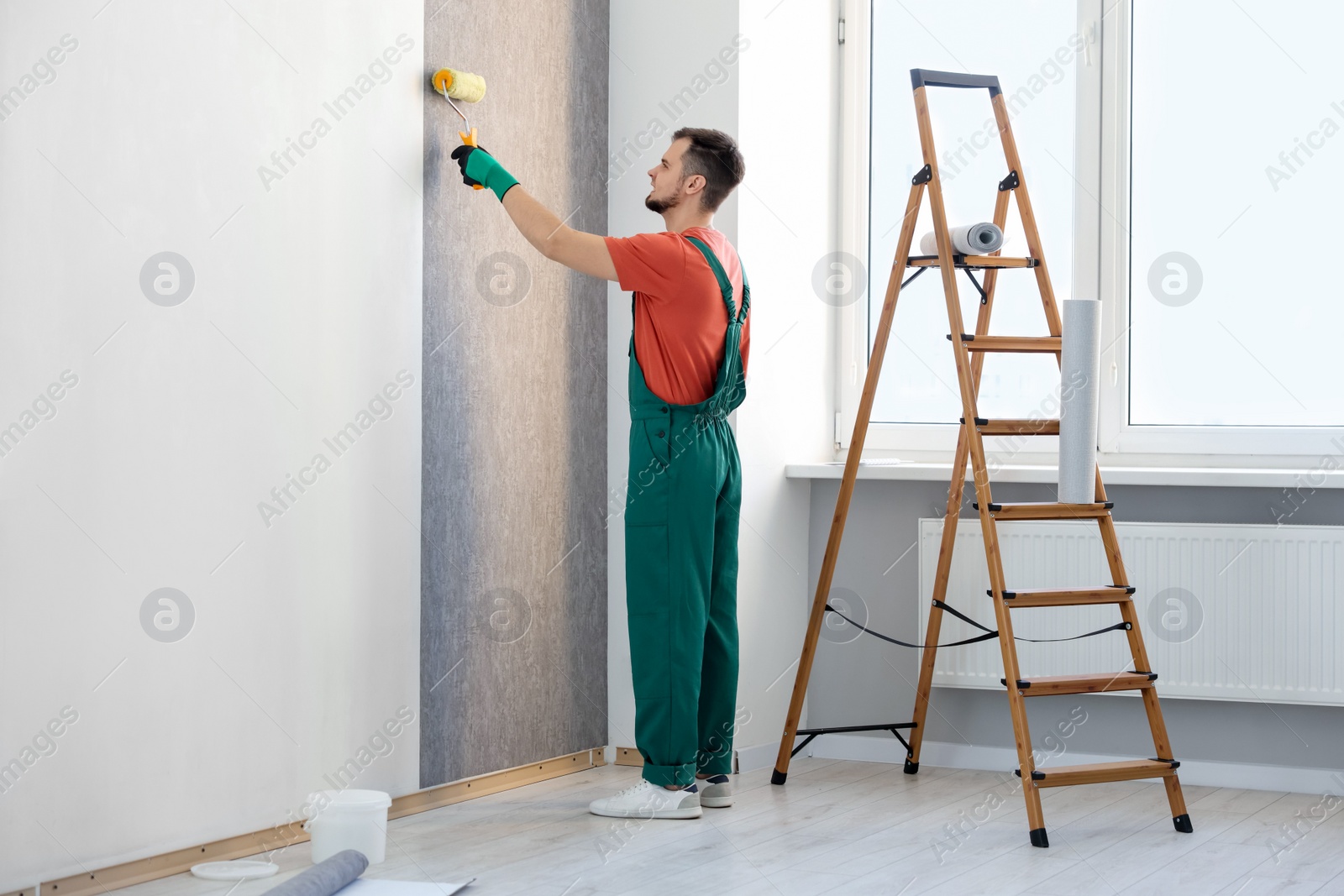 Photo of Man hanging stylish gray wallpaper in room