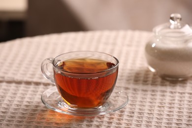 Photo of Aromatic tea in cup, saucer and sugar on table